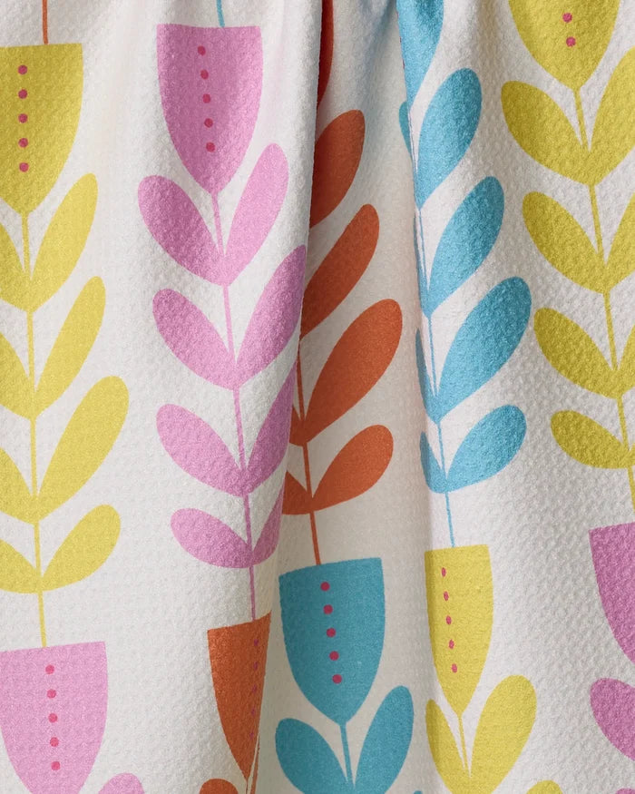 Close-up of the absorbent Folk Art Tulips dish towel by Lizzie Clark, featuring a colorful floral pattern with stylized plants in pots on a white, textured background.