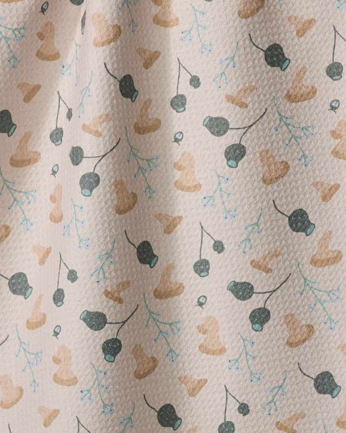 Forage by Amberleigh Adoff is a cream tea towel with a textured surface, patterned with brown cowboy hats, black cherries, and blue branches. Made from recycled materials, it brings playful charm and eco-friendly style to your kitchen.