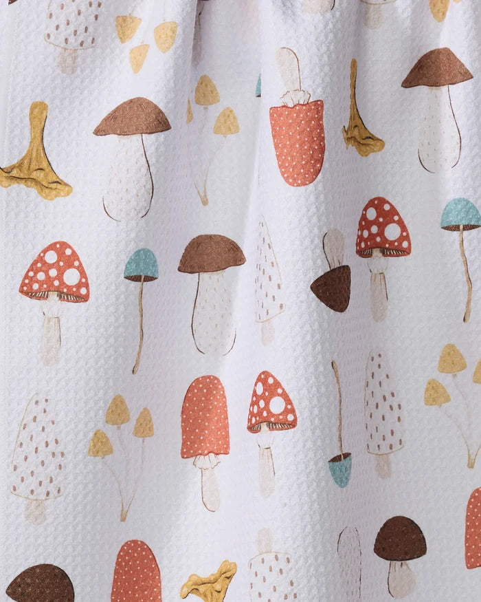 The Sara Mari "Foraging" dish towel features a white textured, absorbent fabric decorated with a colorful hand-drawn mushroom pattern in brown, red, yellow, and blue.