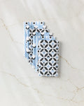Four Anette Heiberg "Forest Findings" cloth napkins—two blue with white and dark geometric designs and two white with blue and black circles—are neatly stacked on marble, offering an eco-friendly paper towel alternative.