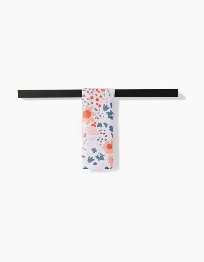 The Forest Foliage patterned bar towel by Coit Creative, made from absorbent Geoweave fabric, hangs neatly over a sleek black towel bar against a white background.