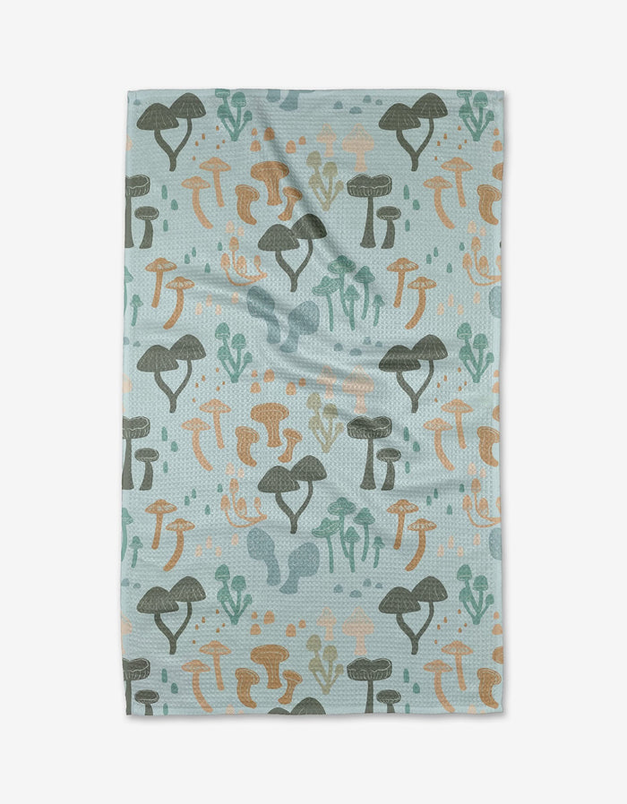 The Forest Friends Tea Towel by Amberleigh Adoff is a rectangular, light blue towel with a repeating green, brown, and orange mushroom pattern. Ultra-absorbent with a soft look, it’s perfect for any kitchen.
