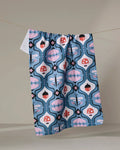 The Anette Heiberg "Forest Garden" dish towel, featuring a blue, pink, and red abstract floral and mushroom pattern, hangs on a line against a neutral background.