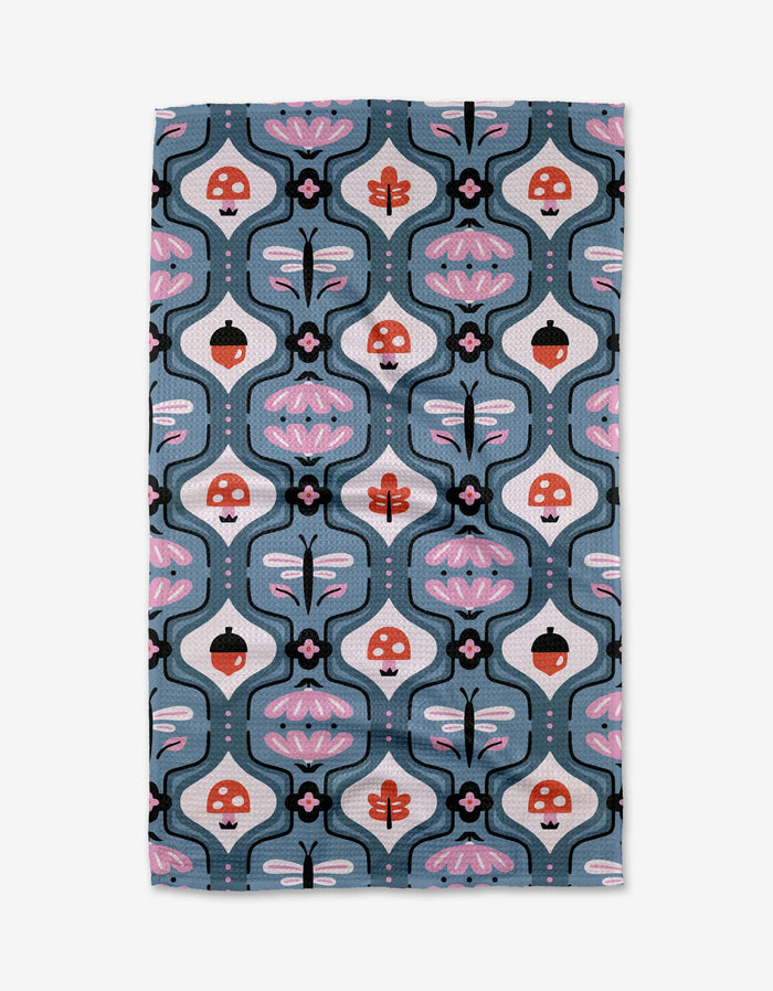 The Forest Garden towel by Anette Heiberg is ultra-absorbent and showcases whimsical mushrooms, dragonflies, and abstract florals in pink, red, black, and white on a blue background.