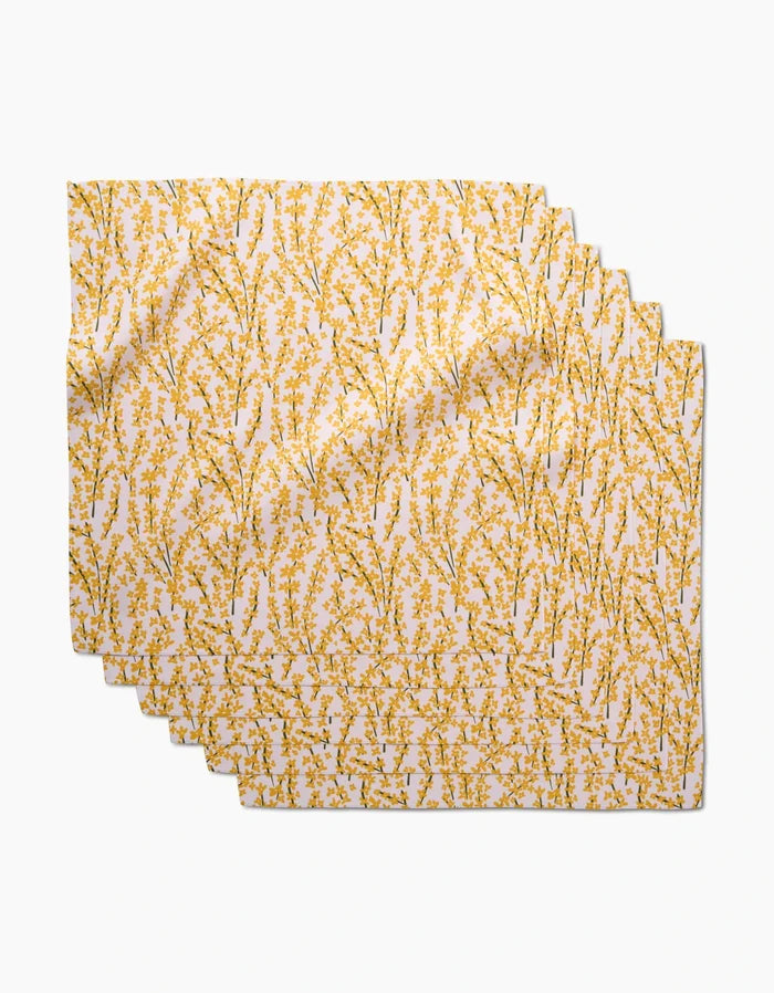 Four Forsythia Floral placemats by Kayla Ann are stacked, each crafted from soft Geosuede fabric with a white background and a yellow floral branch pattern evenly distributed across the surface.