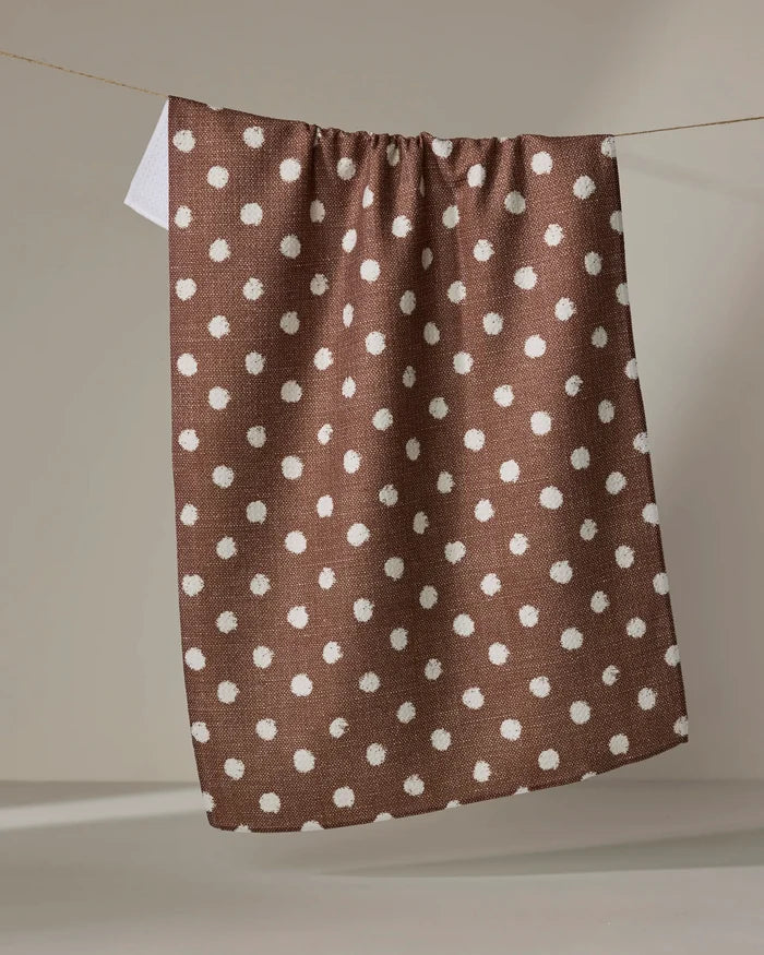 The Geometry Freckle Off White absorbent kitchen towel hangs from a clothesline against a neutral background.