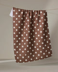 The Geometry Freckle Off White absorbent kitchen towel hangs from a clothesline against a neutral background.