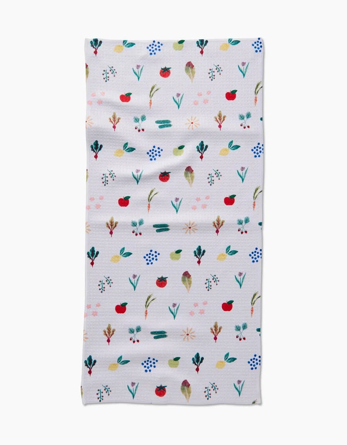 The Fresh Produce Geoweave cloth by Brittany Jepsen is a rectangular, ultra-absorbent white towel adorned with colorful, hand-painted flowers, leaves, and red fruits arranged in horizontal rows.