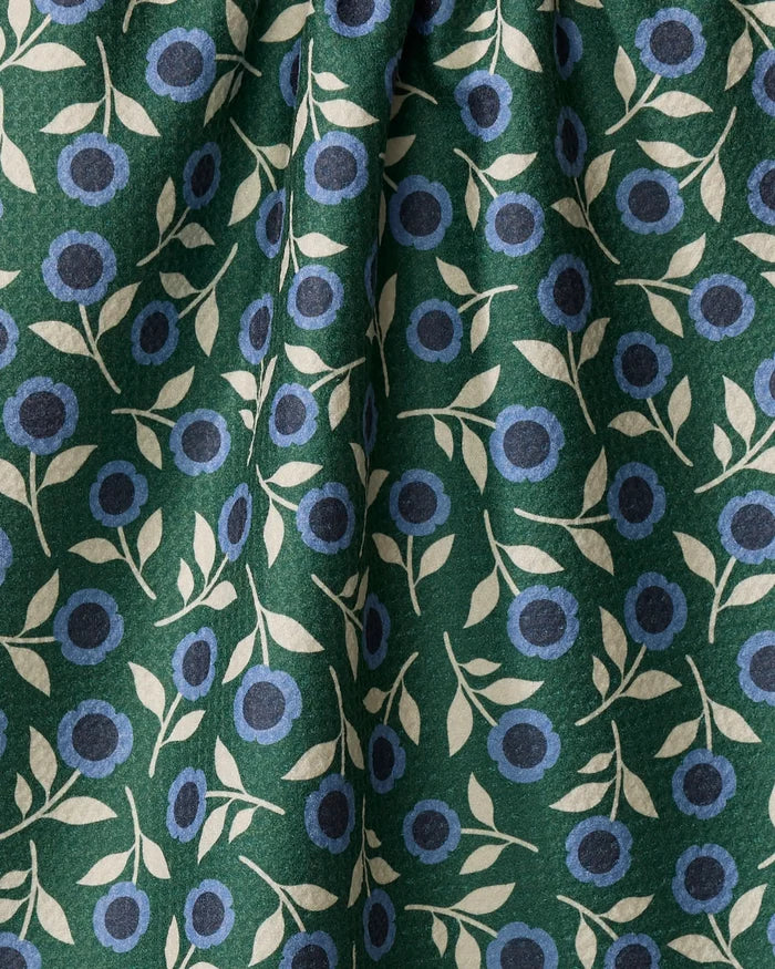 Friendly Floral Blue by Megan Kampa is a recycled kitchen towel featuring blue circular flowers and light beige leaves on green fabric, combining stylish, nature-inspired design with eco-friendly appeal.