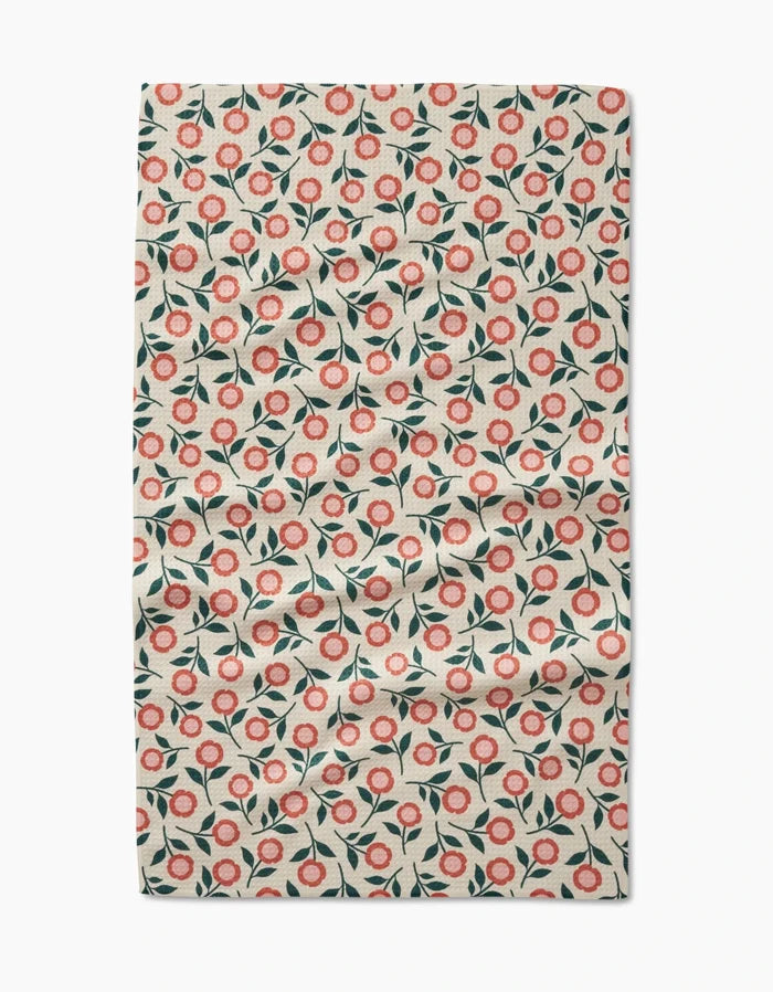 Friendly Floral Peach by Megan Kampa features a Geoweave fabric with small red and pink flowers, green leaves, and a light beige background. This ultra-absorbent towel may show some visible creases and folds.