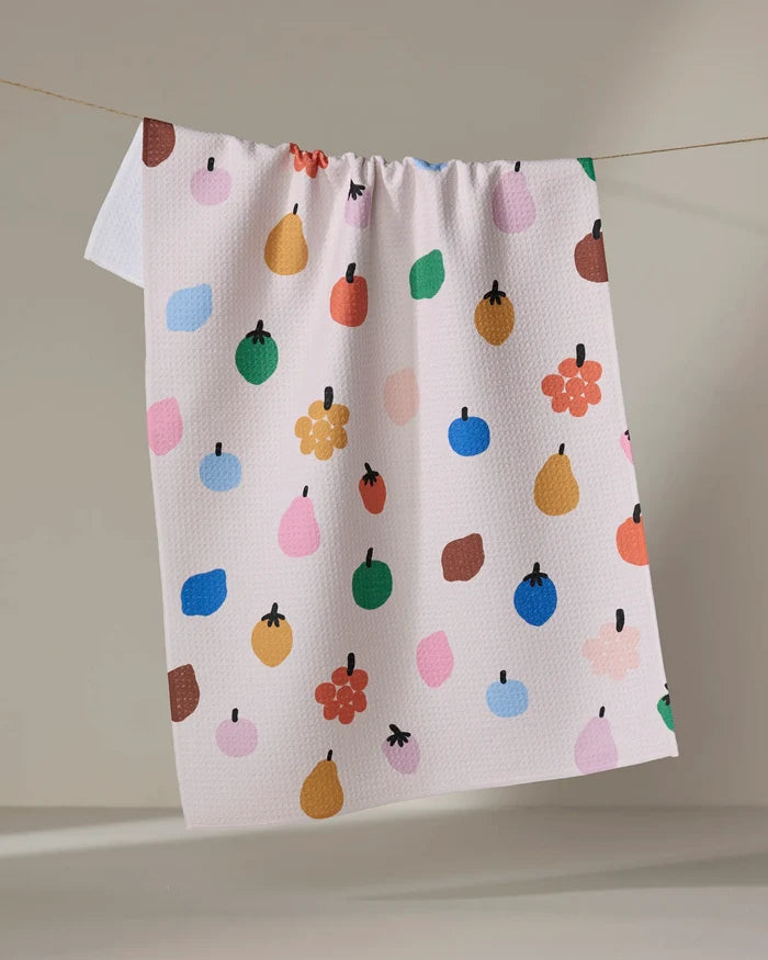 The "Fruit Basket" tea towel by Jennifer Bouron is made from recycled materials and features a lively pattern of colorful apples, pears, berries, and dots on a neutral background, bringing cheerful charm to your kitchen.