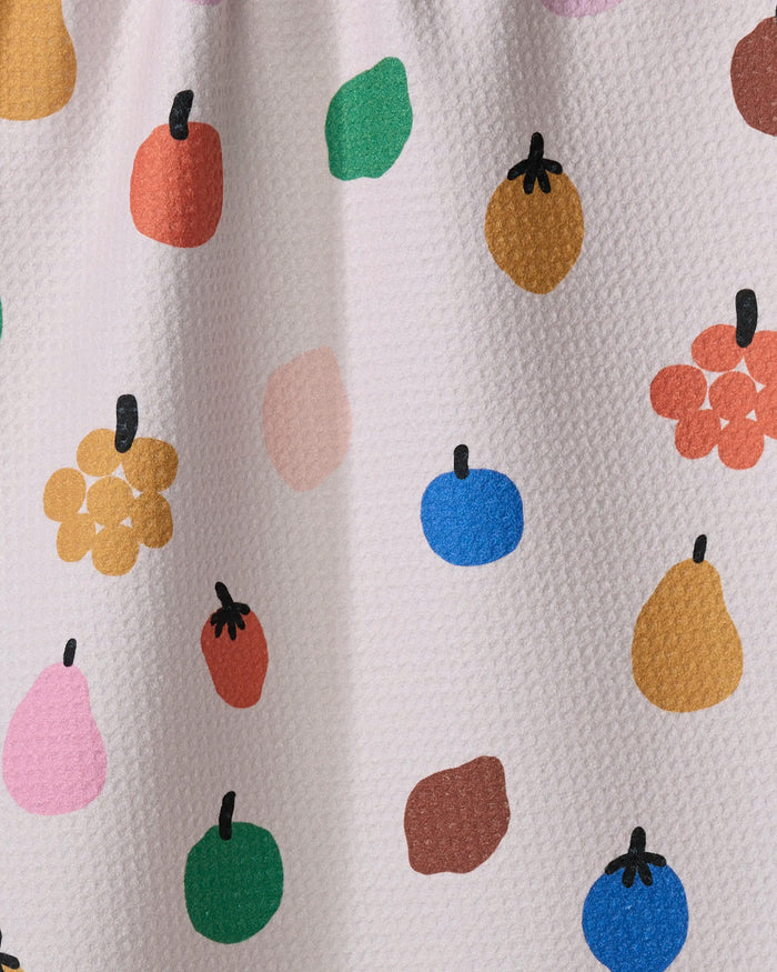 Fruit Basket by Jennifer Bouron is a textured white tea towel made from recycled materials, decorated with playful, abstract fruit shapes in pink, green, blue, yellow, orange, and red—each with a simple black stem.