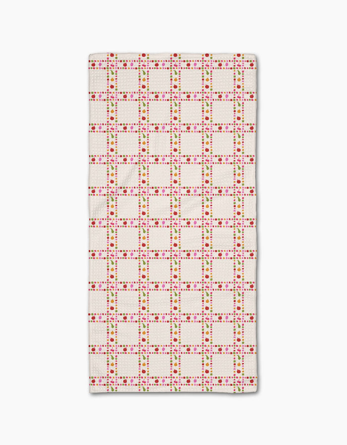 The Fruits Plaid by Geometry is a rectangular white bar towel with a grid of red and pink dots plus green accents forming squares, evenly repeated on Geoweave fabric.