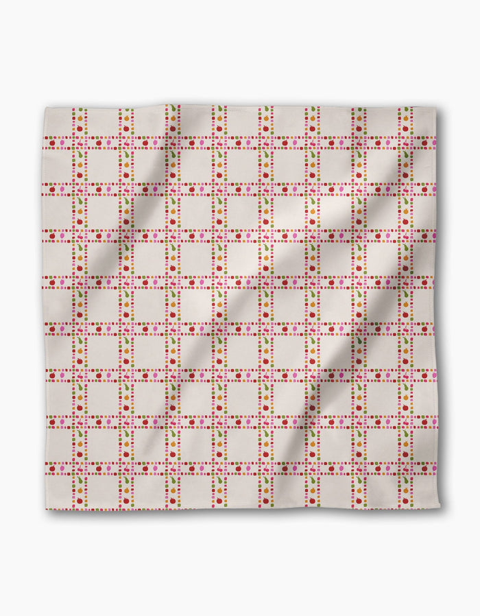 Fruits Plaid by Geometry is a rectangular Geosuede cloth featuring a grid of pink, red, and green squares and dots on white. Made from recycled materials, the fabric shows slight wrinkles.