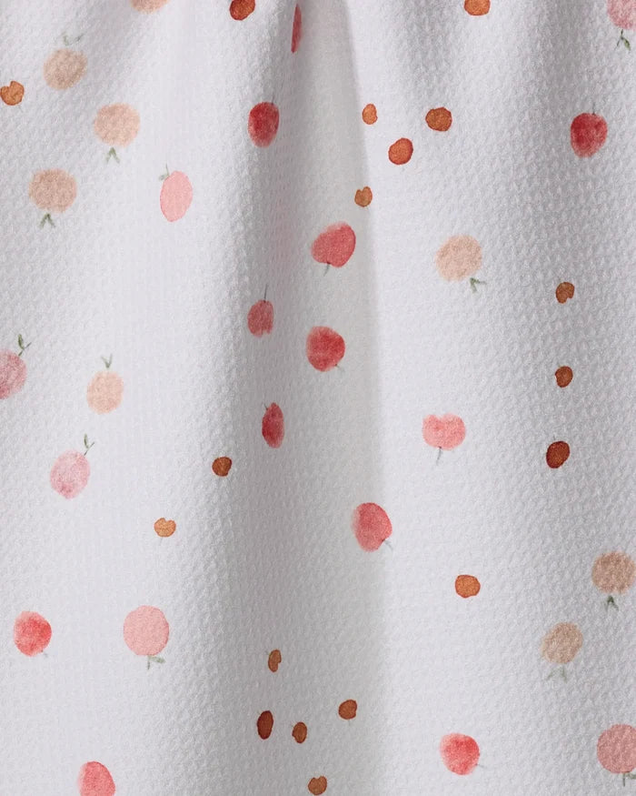 The Fruity tea towel by Anee Shah is white and textured, made from recycled materials, and features scattered red, pink, and orange watercolor-style dots and circles.