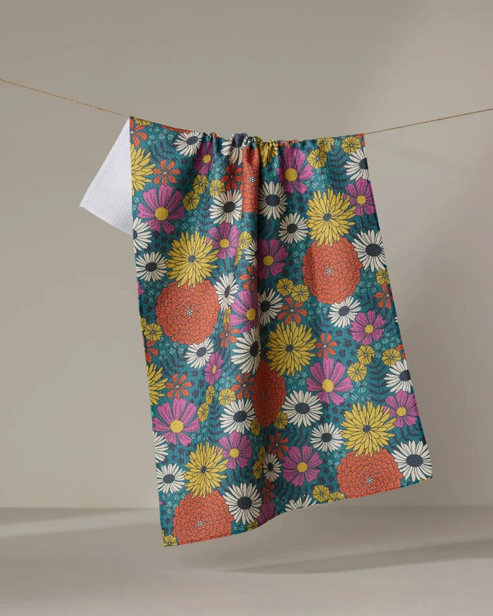 The "Funky Fleurs" tea towel by Megan Kampa features a vibrant floral design in orange, yellow, pink, and white—ultra-absorbent and ideal for brightening any kitchen.