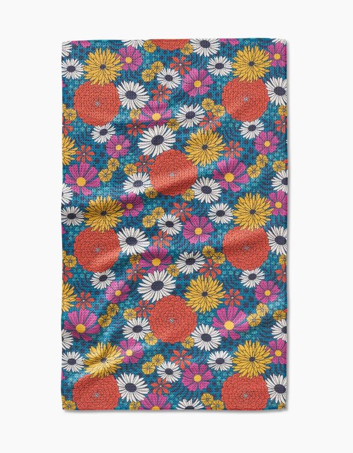 The Funky Fleurs tea towel by Megan Kampa features red, white, yellow, and pink flowers on blue Geoweave fabric with a textured finish and slight folds.