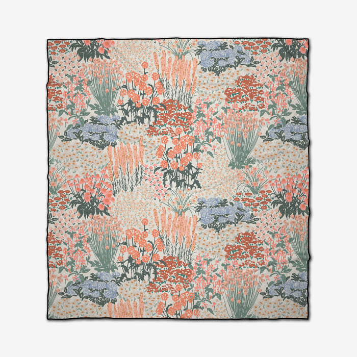 The Garden Bloom square scarf by Hufton Studio features a vintage-inspired floral pattern in soft orange, green, blue, and cream, evoking the charm of a recycled beach blanket with its clusters of flowers and grasses.