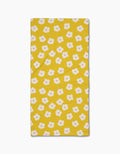 The Sara Mari Garden Crush Bar Towel is yellow and rectangular, featuring a Geoweave fabric with small white flowers with orange centers evenly spaced across the surface.