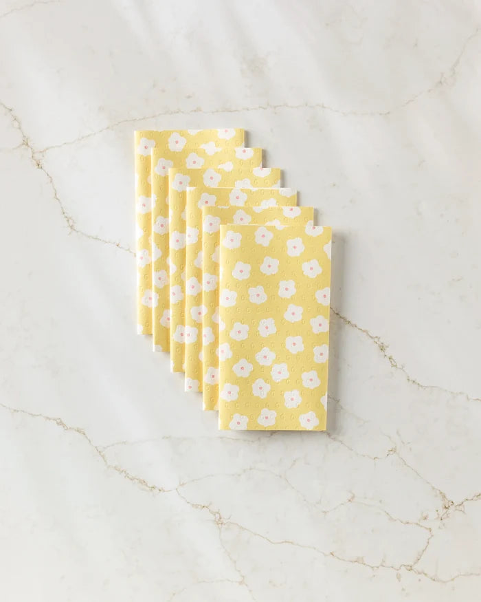 Six yellow "Garden Crush" reusable paper towels by Sara Mari, featuring a white and pink floral pattern, are neatly stacked on a light brown-veined white marble surface.