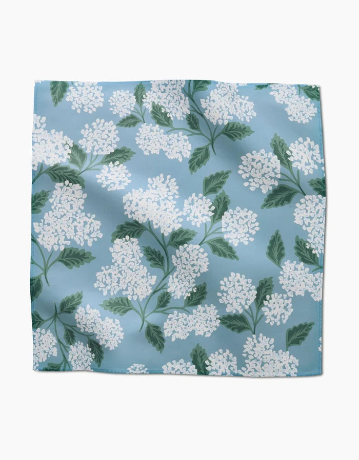 The Garden Of Edith by GEOMETRY is a square Geosuede scarf featuring white lilac flowers and green leaves on a light blue background.