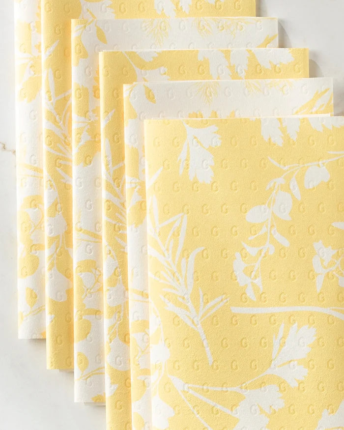 Five "Garden of Gold" reusable paper towels by GEOMETRY, featuring white floral patterns on a yellow background, are fanned out on a light surface—combining charm and sustainability for your kitchen.