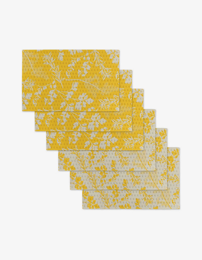 Six rectangular yellow Garden of Gold napkins by GEOMETRY, featuring white floral and leaf patterns, are fanned out on a white background—a reusable, eco-friendly Not Paper Towels alternative.
