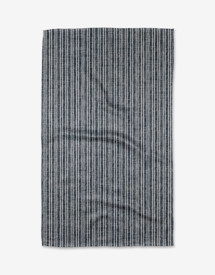 The Garff Blue Tea Towel by Becki Owens features vertical navy blue and white stripes, laid flat on a white background, and is made from durable Geoweave fabric.
