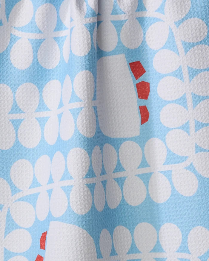 Close-up of the Gemini kitchen towel by Happy Hemera, showcasing its white geometric floral pattern and small red accents on a blue background. Made from recycled materials for an eco-friendly choice.