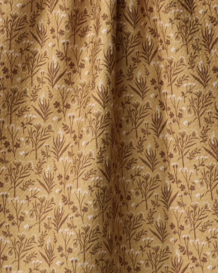 The Golden Fall Flowers tea towel by Danelys Sidron features a detailed botanical pattern in golden brown shades. Made from ultra-absorbent recycled materials, it has a soft texture and gentle folds for added elegance.