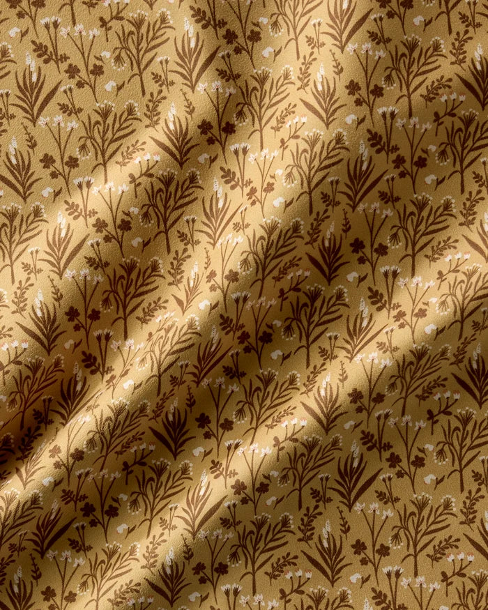 Golden Fall Flowers by Danelys Sidron features gold fabric with a brown and white floral pattern of small flowers and leaves. These reusable napkins add texture and depth—perfect for an elegant dinner napkin set.