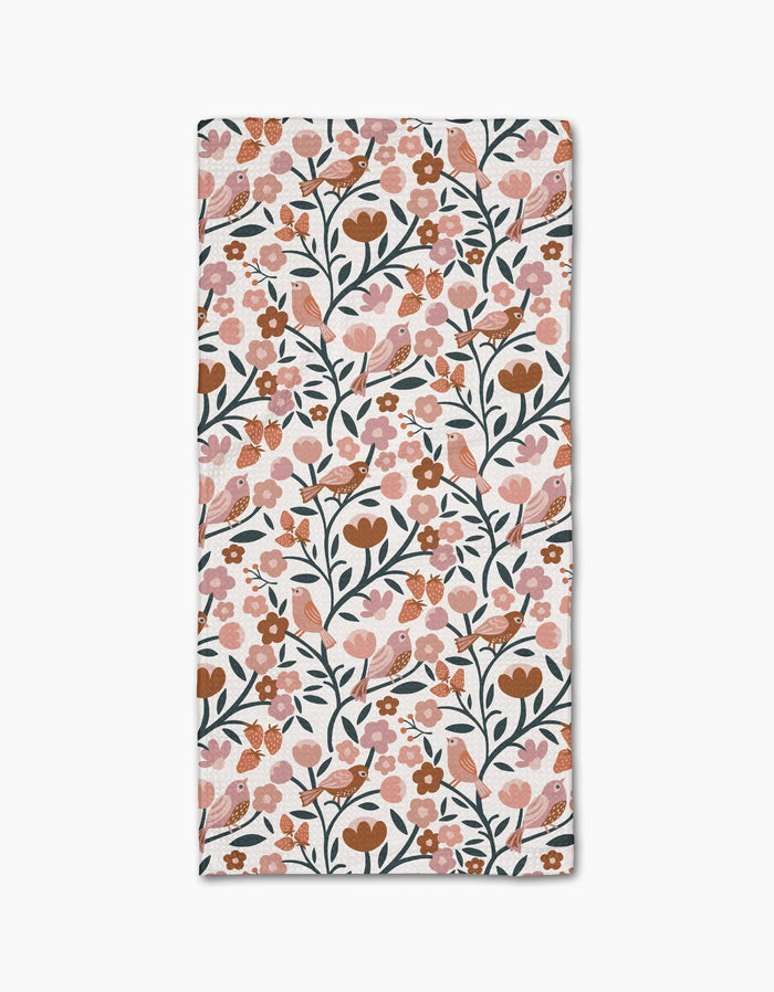 The Golden Hour Park Lane bar towel by Charlie Rowan Designs features a rectangular shape with a repeating pattern of pink, orange, and brown flowers, green stems and leaves, birds, and berries on white Geoweave fabric made from recycled materials.