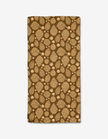 The Golden Pines Bar Towel by Danelys Sidron is a rectangular brown towel made from recycled materials, featuring a repeating pattern of tan pine cones and acorns on a white background.