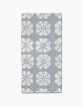 The Gracie Bar Towel by Geometry is rectangular, gray, and made with Geoweave fabric, featuring rows of large white hibiscus flowers on a plain background.