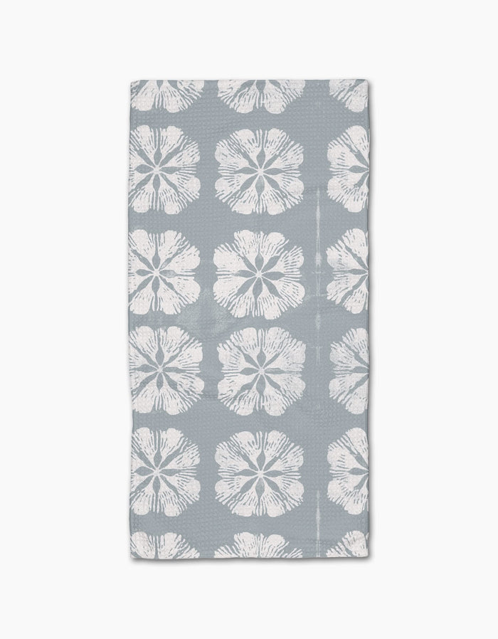The Gracie Bar Towel by Geometry is rectangular, gray, and made with Geoweave fabric, featuring rows of large white hibiscus flowers on a plain background.