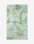 The Green Kites tea towel by GEOMETRY showcases an abstract geometric pattern of green, yellow, and blue lines on white, made from eco-friendly Geoweave fabric.
