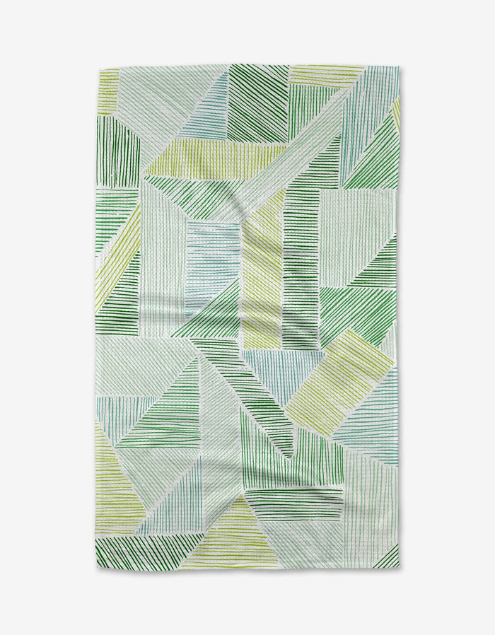 The Green Kites tea towel by GEOMETRY showcases an abstract geometric pattern of green, yellow, and blue lines on white, made from eco-friendly Geoweave fabric.