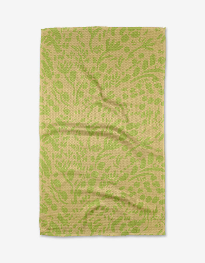 The Green Spring tea towel by Sareka Unique is rectangular, olive green and beige with a botanical leaf and flower pattern, made from recycled materials, and shown flat on a white background.