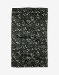 The Green Winter Petal by Katie OShea is a rectangular black recycled kitchen towel with a dense floral and leaf pattern in light gray and white, displayed flat on a white background.