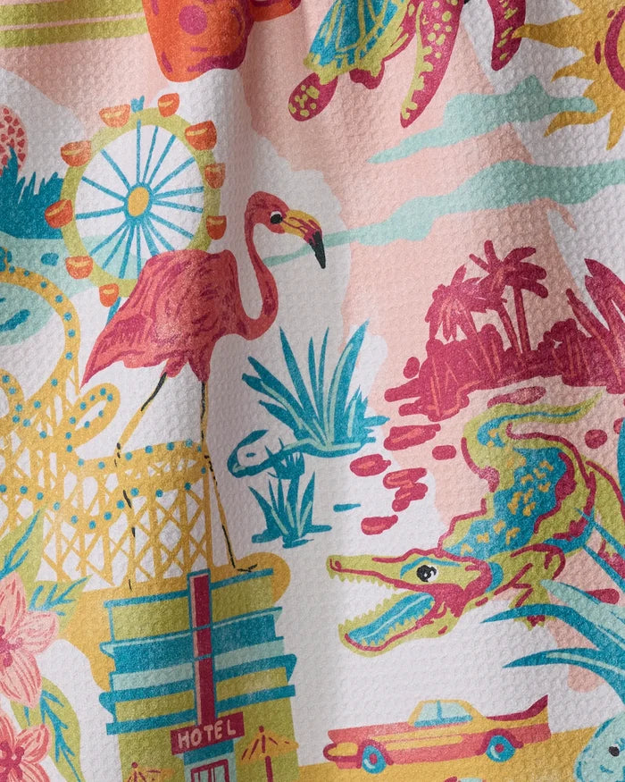 The "Greetings From Florida" kitchen towel by Geometry showcases a colorful, retro design with a ferris wheel, flamingo, palm trees, alligator, hotel, lily pads, and yellow car on soft recycled fabric.