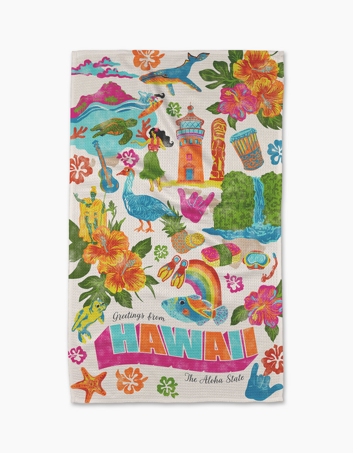 The Geometry "Greetings From Hawaii" tea towel features vibrant Hawaiian-themed illustrations and “Greetings from HAWAII The Aloha State” at the bottom. Ultra-absorbent, it’s perfect for adding color and charm to your kitchen.