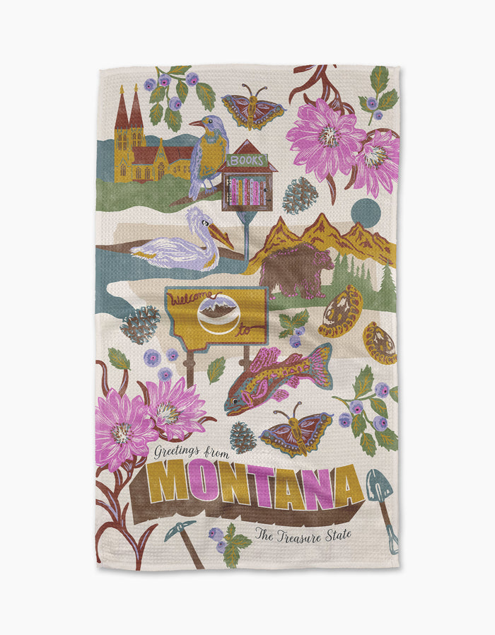 The Geometry "Greetings From Montana" tea towel features vibrant illustrations of Montana icons—flowers, bison, trout, mountains, butterflies, landmarks—and text “Greetings from Montana, The Treasure State.” Made from recycled materials.