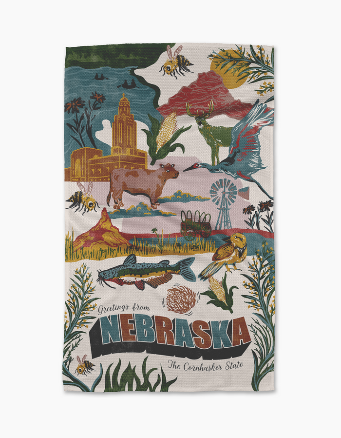 The Geometry "Greetings From Nebraska" towel is ultra-absorbent and features colorful illustrations of cows, birds, bees, wildflowers, the State Capitol, a windmill, and scenic Nebraska landscapes.