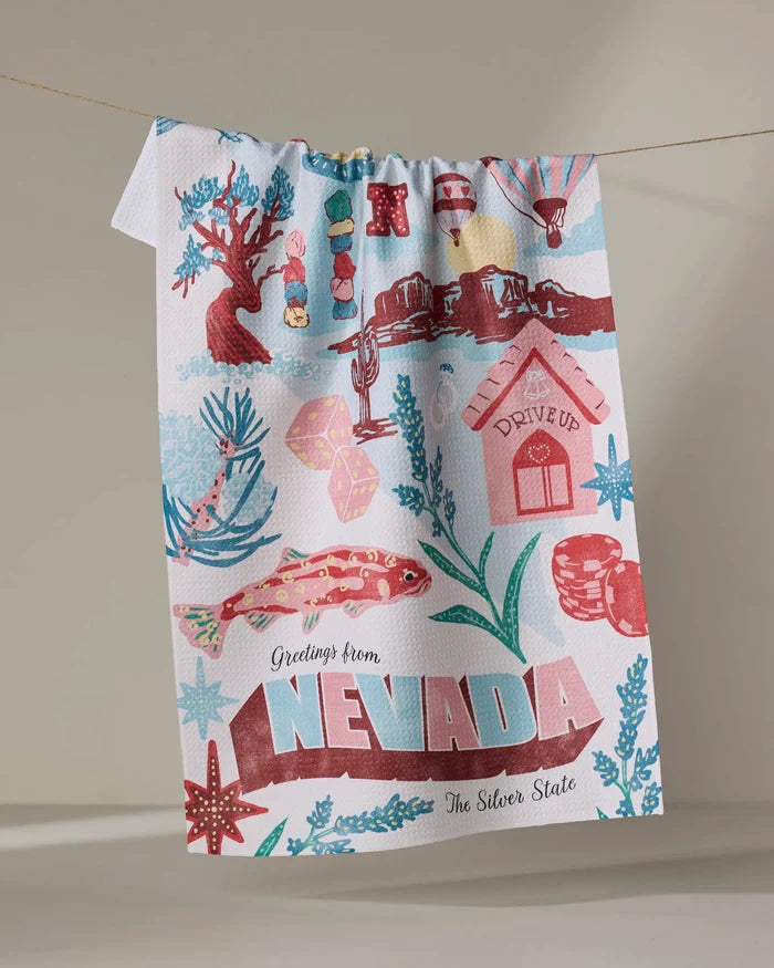 The Geometry Greetings From Nevada tea towel features colorful Nevada symbols—cactus, lizard, playing cards, gems, mountains, and bold “Greetings from NEVADA The Silver State”—and adds quick-drying charm to any kitchen.