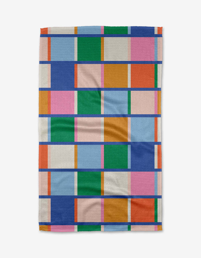 The Grid blanket by Jennifer Bouron features rectangles in blue, pink, orange, green, and white separated by bold blue lines—crafted from recycled materials for an eco-friendly touch.