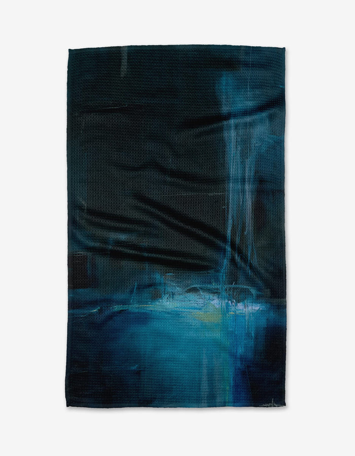 The Grotto tea towel by Jennifer Janesko features abstract blue and black patterns with lighter blue and white brushstrokes, accented by vertical streaks. Crafted from recycled materials, its a stylish, eco-friendly choice for your home.