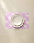 A white bowl and plate are stacked on the Geometry Hairy Check Pink recycled placemat, set on a light beige surface under soft lighting.