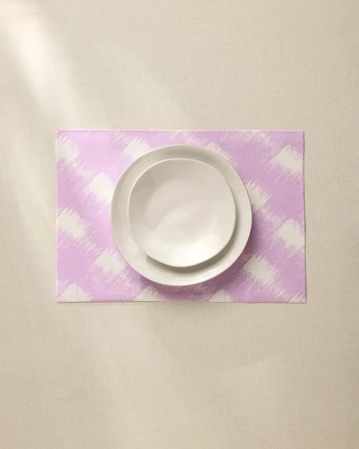 A white bowl and plate are stacked on the Geometry Hairy Check Pink recycled placemat, set on a light beige surface under soft lighting.