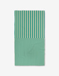 The GEOMETRY Half and Half is a rectangular Luxe Bath Towel featuring vertical teal and cream stripes—wide on top, thin below—made from ultra-absorbent recycled materials, shown on a plain white background.