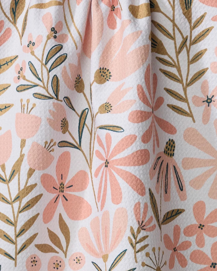 Close-up of Halia, a recycled kitchen towel by Amy MacCready, showcasing textured fabric adorned with pink and beige flowers and green leaves on a light background.